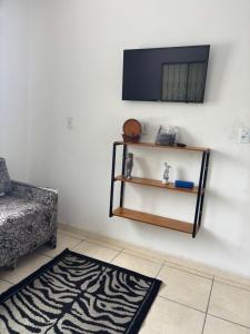 a room with a television on a wall with a rug at Casa 28 de agosto climatizada e aconchegante in Manaus