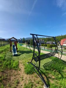 a park bench in a field with a playground at Domki nad Borem in Male Ciche