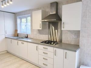 une cuisine avec des armoires blanches et un four à plaques de cuisson dans l'établissement Classy double room Salford Detached house, Plab, à Manchester