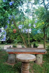 a bench sitting in front of a tree with blue flowers at Ananda Home Stay and Restaurant in Tangalle