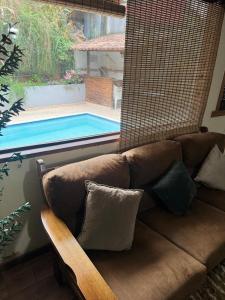 a brown couch sitting next to a swimming pool at Casa com piscina em Nogueira - 6 pessoas in Araras Petropolis