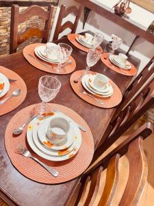 a wooden table with plates and wine glasses on it at Casa com piscina em Nogueira - 6 pessoas in Araras Petropolis