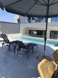 a patio with a table and chairs and an umbrella at Αriadne in Porto Rafti
