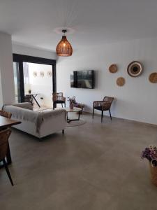a living room with a couch and chairs and a tv at Αriadne in Porto Rafti