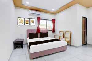 ein Schlafzimmer mit einem Bett und einem Tisch und einem Fenster in der Unterkunft Hotel O RamdevGarh Resort in Ahmedabad