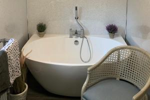 eine Badewanne mit Dusche und Stuhl im Badezimmer in der Unterkunft Remarkable 2-Bed Cottage in tranquil setting in Wooler + 21 Fotos