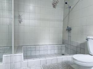 a white tiled bathroom with a toilet and a shower at Gran Via Hostel in Punta Arenas +6 photos