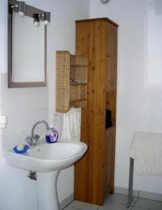 une salle de bain avec un lavabo blanc et un meuble en bois dans l'établissement Komforthaus Mit Traumgarten Und Meerblick, à Plouha 33 autres photos