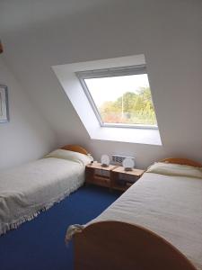 deux lits dans une chambre avec une fenêtre dans l'établissement Komforthaus Mit Traumgarten Und Meerblick, à Plouha