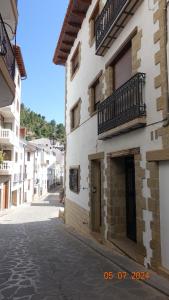 an alley with a white building with a balcony at La Buhardilla del Cielo in Villahermosa del Río
