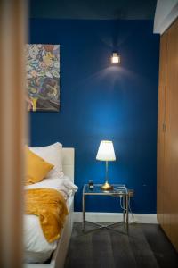 a blue bedroom with a bed and a table with a lamp at Berwick Soho Suites by Aureva Residences in London