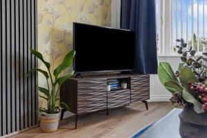 a flat screen tv sitting on a stand in a living room at Greenview in Spinney Hill