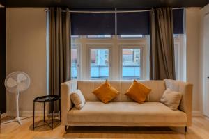 een bank met kussens voor een raam bij Berwick Soho Suites by Aureva Residences in Londen