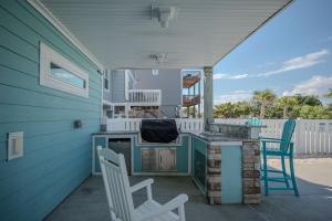een patio met 2 stoelen, een tafel en een fornuis bij Wait N Sea by Oak Island Accommodations in Oak Island