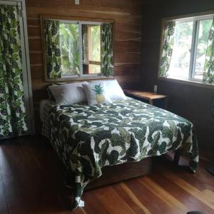 a bedroom with a bed with a comforter and two windows at Barton Creek Unique Resort in Sayab Camp +8 photos