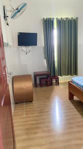 a room with a bed and a table and a tv at Nhà Nghỉ PHÚC THỊNH 