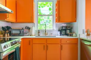 an orange kitchen with a sink and a window at Jungle House Columbus Short North Downtown Free Parking - Steps to Convention Center & Nationwide Arena - 2BR Luxury Home - Sleeps 8 - Over 5,800 Five Star Stays in Columbus