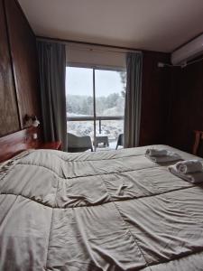 een slaapkamer met een groot bed met een groot raam bij Village in La Cumbrecita +2 foto's