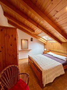 プレダッツォにあるAppartamento Genzianaの大きなベッドと木製の天井のある寝室