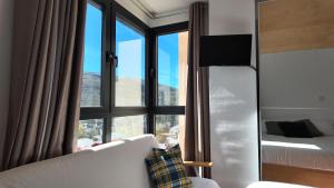 ein Zimmer mit einem großen Fenster mit einer Couch und einem Fernseher in der Unterkunft Apartamento Premium Snow Gorbea - Vistas a pistas, wifi y parking gratis Zona Baja in Sierra Nevada