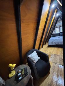 een woonkamer met een stoel en een bed bij Recanto - Chalé Boa Vista in Jaraguá do Sul