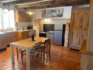 eine Küche mit Tisch und Stühlen und einem Kühlschrank in der Unterkunft Domaine de Cazal - Gîte 2 pers avec piscine au cœur de 26 hectares de nature préservée in Saint-Cyprien