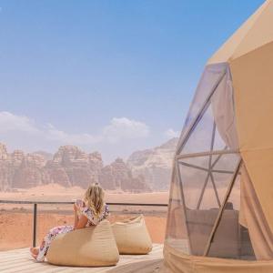 a little girl sitting on a pillow next to a tent at Lunar Mirage Camp in Wadi Rum