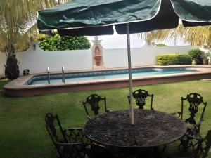 a table with an umbrella in front of a pool at Casa Vergel in Temixco