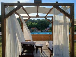 a wooden pergola with white curtains and a bench at 7 kruna Žiče in Žiča