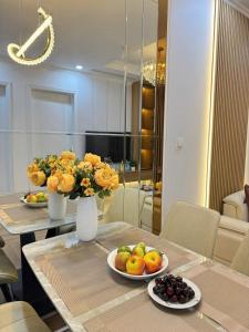 une table de salle à manger avec deux assiettes de fruits et de fleurs dans l'établissement Vinhomes Times City Hai Bà Trưng Hà Nội Jenny Apartment, à Hanoï 33 autres photos