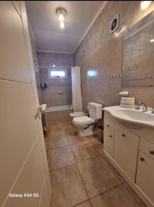 a bathroom with a toilet and a sink and a mirror at Apart Hotel Naga Huel in Sierra de la Ventana