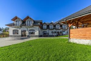 a large house with a green lawn in front of it at Pensjonat Perła Pienin in Grywałd