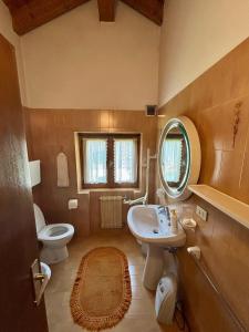 um banheiro com uma pia, um vaso sanitário e um espelho em Appartamento Sass Aut em Soraga