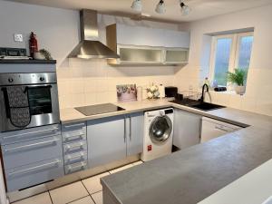 a kitchen with stainless steel appliances and a washer and dryer at Superb 2 bed 2 bathroom free parking in Derby