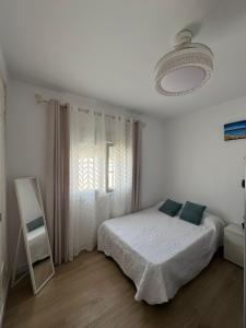 a white bedroom with a bed and a window at La Casita de Community SurfHouse El Palmar in El Palmar +25 photos