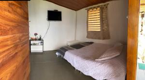 a small bedroom with a bed and a television at Cabaña el mirador del aguila in Quebradanegra