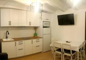 een keuken met witte kasten en een tafel en een televisie bij Casa Bea in Puertomingalvo