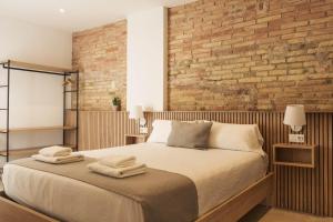 Un dormitorio con una cama y una pared de ladrillo. en ARIQUS Apartments, en Hospitalet de Llobregat