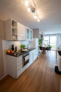 a kitchen with white cabinets and a table in a room at Modernes Apartment - Basel, Kur & Golf in Bad Bellingen