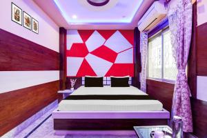 a bedroom with a bed with a red and white wall at Super Collection O New Jalpaiguri Railway Station Formerly Prince Lodge in Siliguri