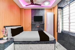 a bedroom with a bed with a tv on the wall at Super Collection O New Jalpaiguri Railway Station Formerly Prince Lodge in Siliguri +27 photos