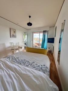 Un dormitorio con una cama grande y una mesa. en Studio cosy avec balcon, en Bagnoles de l'Orne