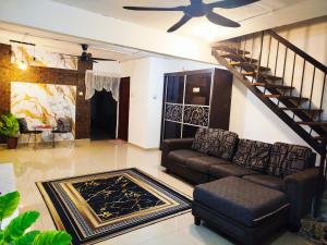 een woonkamer met een bank en een trap bij Asyun Homestay 1 Double Storey House Sg Buloh Town in Sungai Buluh
