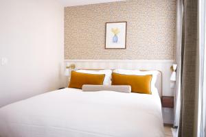 a bedroom with a large white bed with orange pillows at Joli Môme in Paris