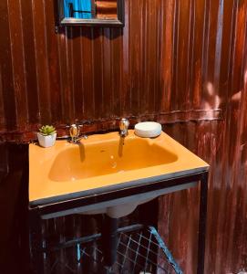 Un lavabo amarillo en un baño con paredes de madera en Ewakanda Backpackers, en Vereeniging