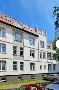 a large white building with a red roof at Apartament Podniebny z Windą in Kluczbork +4 photos