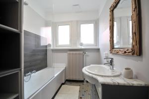 a bathroom with a sink and a tub and a mirror at Gîte du Soleil - close to Europa-Park in Grussenheim +24 photos
