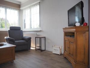 a living room with a chair and a flat screen tv at Gîte du Soleil - close to Europa-Park in Grussenheim