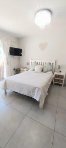 een slaapkamer met een wit bed en een televisie bij Muizenberg lakeside in Lakeside