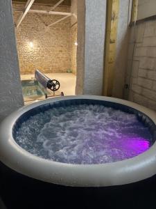 a large tub filled with purple water in a room at maison chaleureuse ,avec piscine, spa, Futuroscope in Jaunay-Marigny